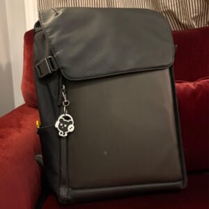 Black bear headphones keychain clipped to a backpack zipper on a red couch