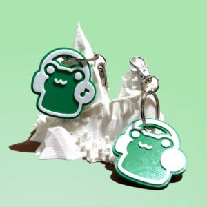 NFC and non-NFC green frog headphones keychains displayed on a white 3D printed mountain stand